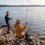 Le père et le fils pêchent la journée d'hiver ensoleillée.