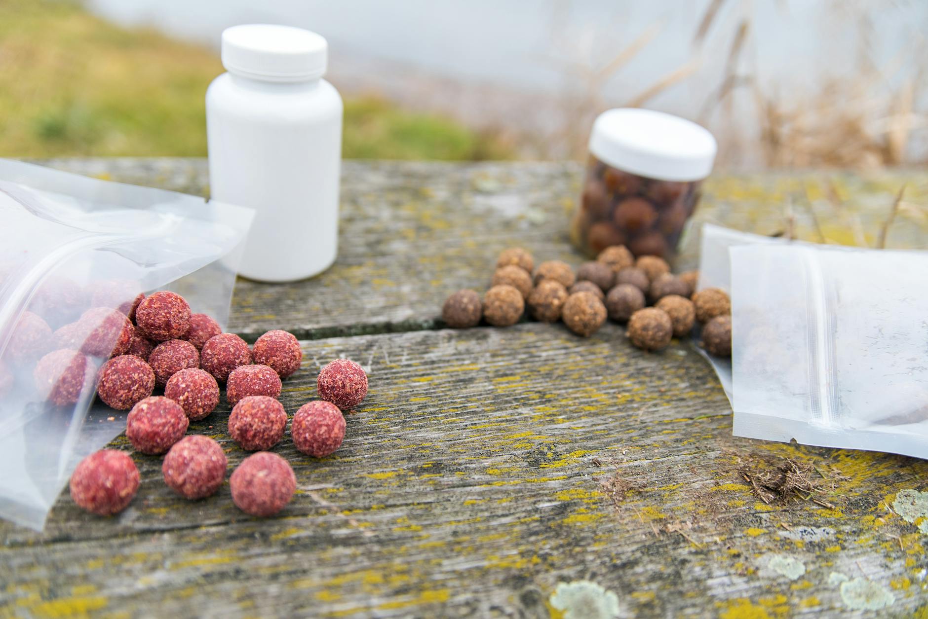 Diverses boules d'appâts colorées sur une table en bois altérée à l'extérieur.