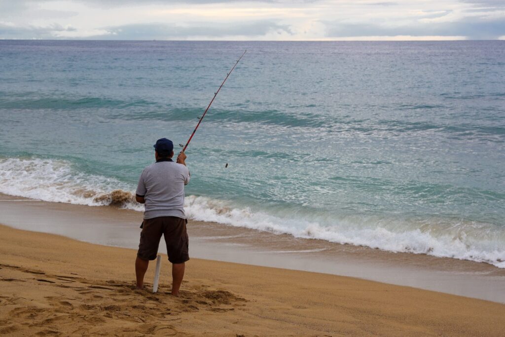 Un pêcheur avec une tige sur la plage.